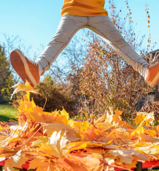 A person jumping in the air wearing orange sneakers with leaves around them linking to sneakers page