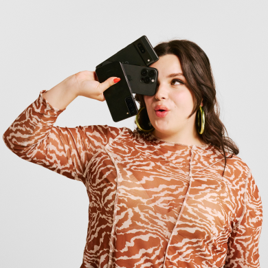 A pleased-looking woman holds several smartphones close to her face. Image links to Refurbished page.