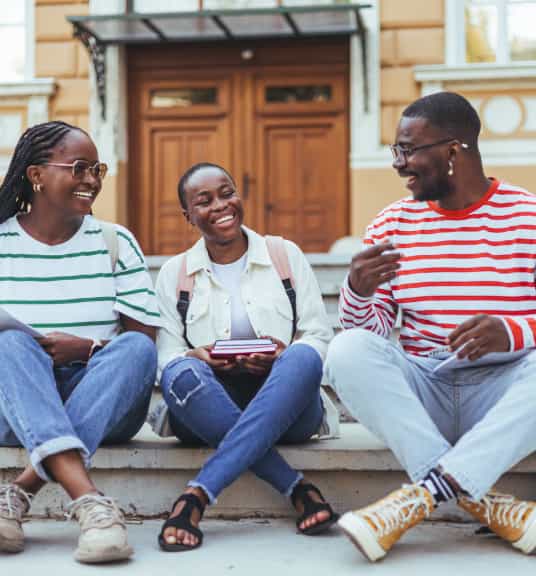 Three Black people smiling on steps