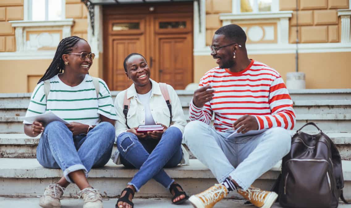 Three Black people smiling on steps