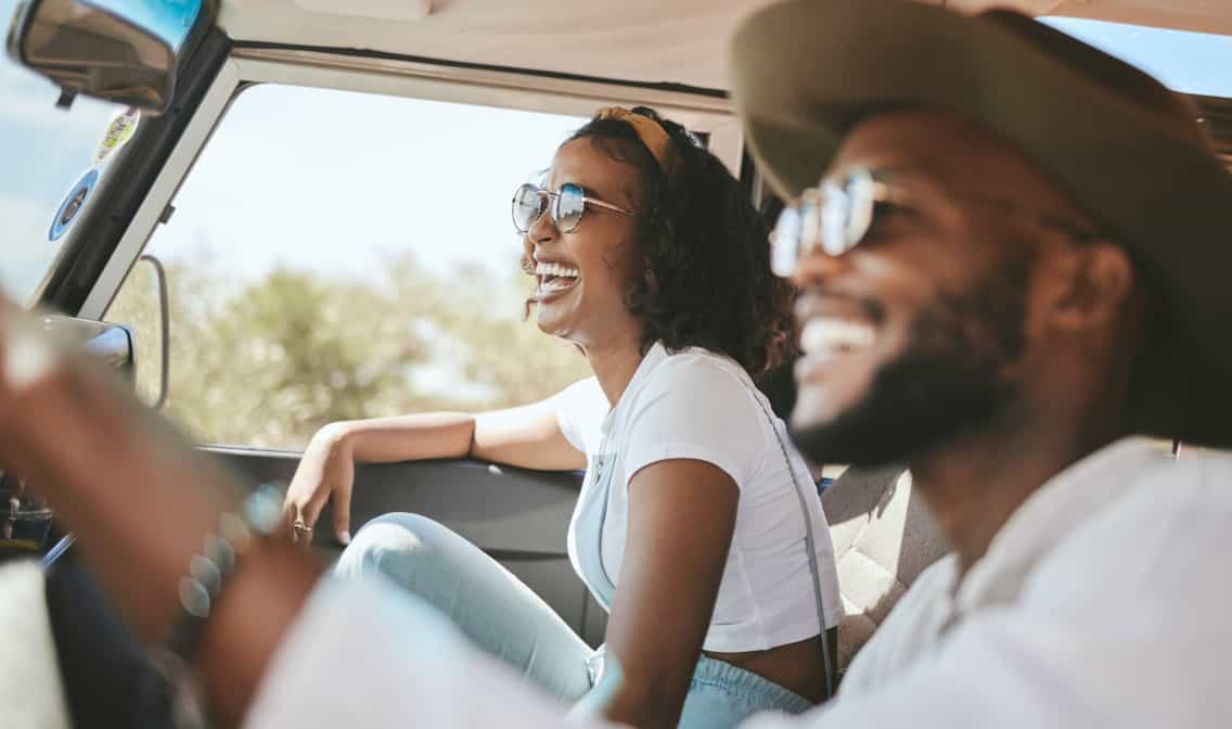 Two people smiling in a car linking to extra 15% off auto parts shopping event