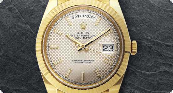 Gold Rolex watch on a dark grey textured background. 