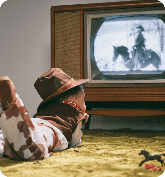 Kid in cowboy costume watching cowboy show linking to retro toys page