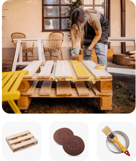 A person painting a pallet table linking to DIY landing page, A wood pallet, Two pieces of brown sandpaper, A paint brush sitting on top of a paint can filled with white paint