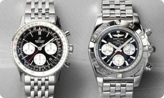 Two silver Breitling watches on a grey background.