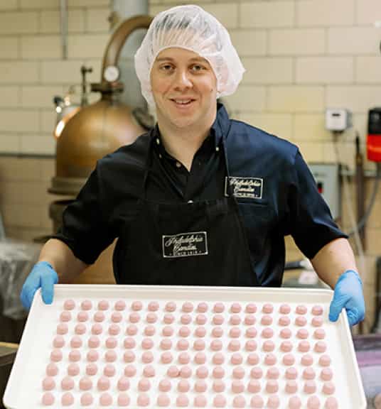 A man holding a tray of pink chocolates linking to Philadelphia Candies eBay store