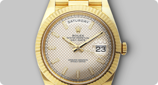 A golden Rolex on a grey background.