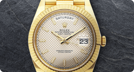 Gold Rolex watch on a dark grey textured background.