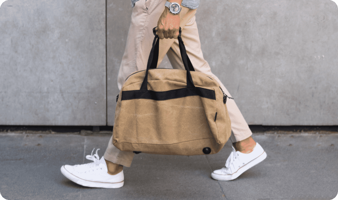 Man walking with duffel bag linking to men's fashion products